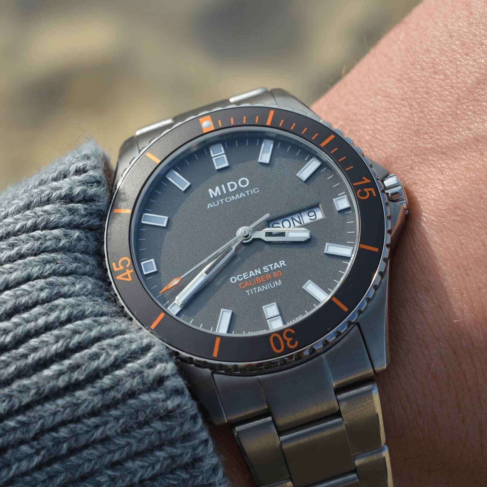 Orologio con quadrante nero e ghiera arancione, cinturino in titanio