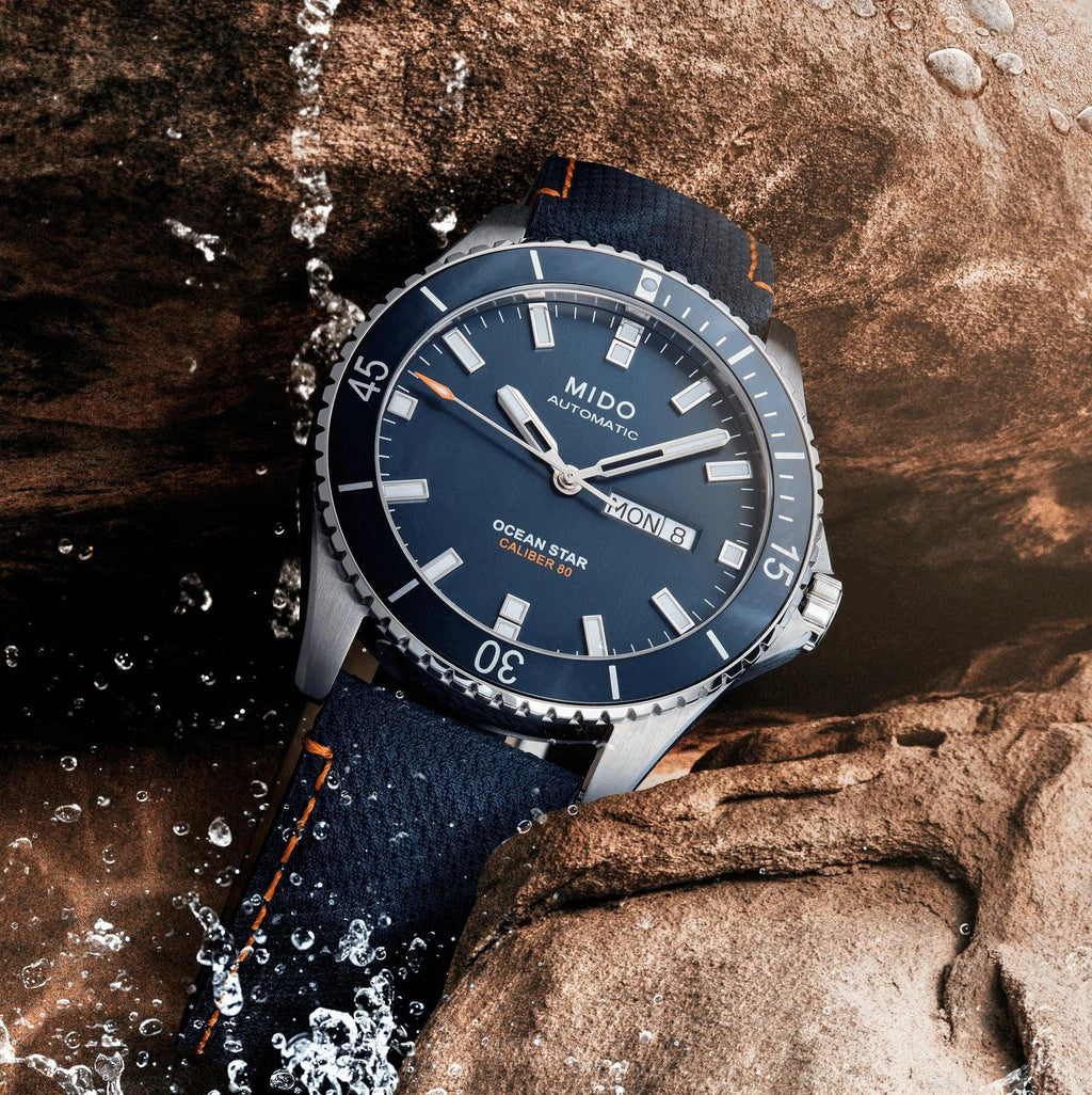 Orologio Mido con quadrante blu, dettagli luminosi e lunetta, cinturino blu con cuciture