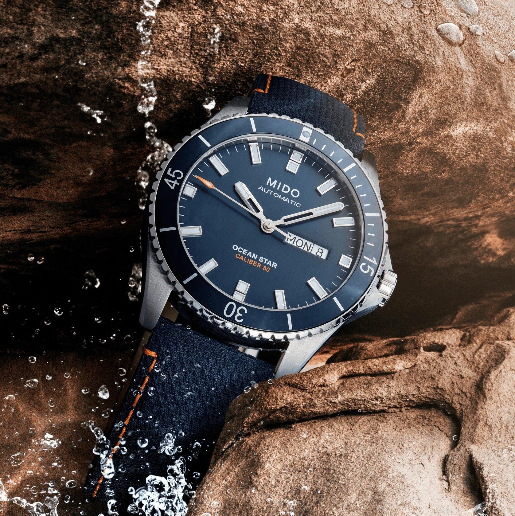 Orologio Mido con quadrante blu, dettagli luminosi e lunetta, cinturino blu con cuciture