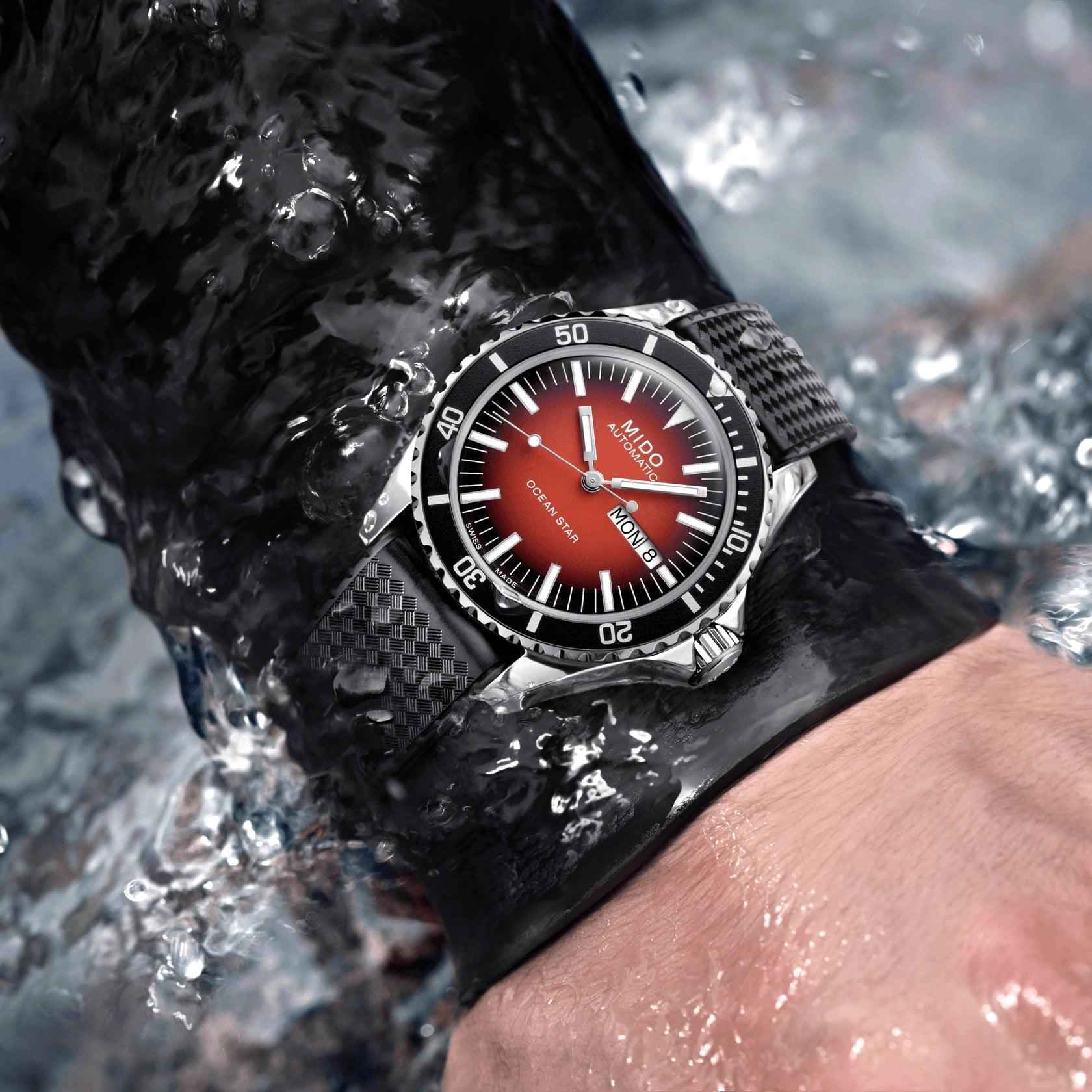 Orologio automatico con quadrante rosso sfumato, cinturino nero, sul polso bagnato