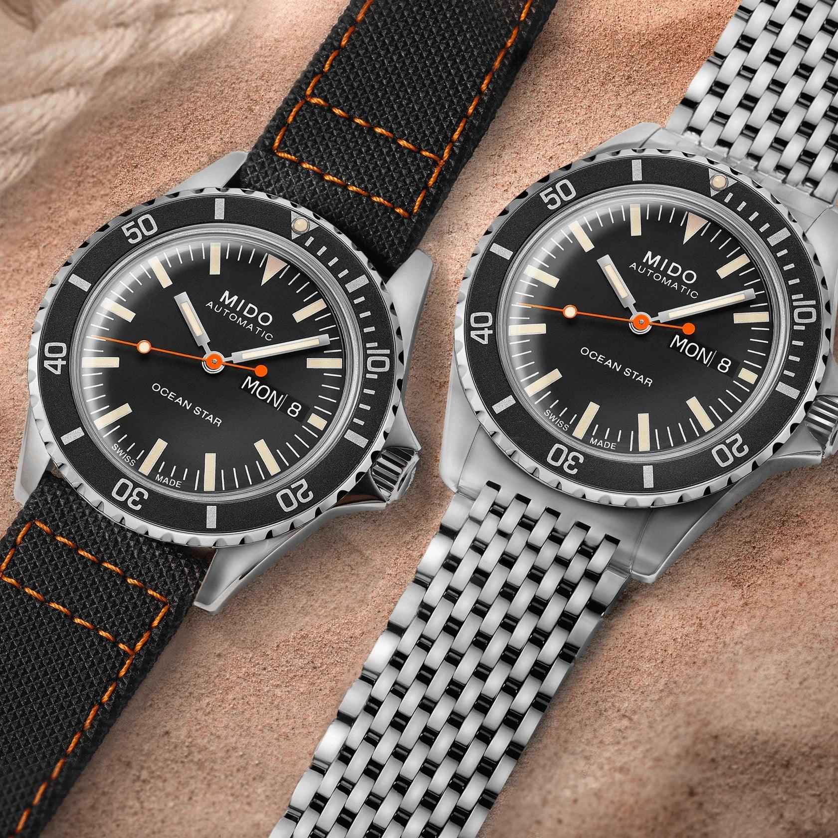 Orologi con quadrante nero: uno con cinturino nero cuciture arancioni, uno con bracciale acciaio