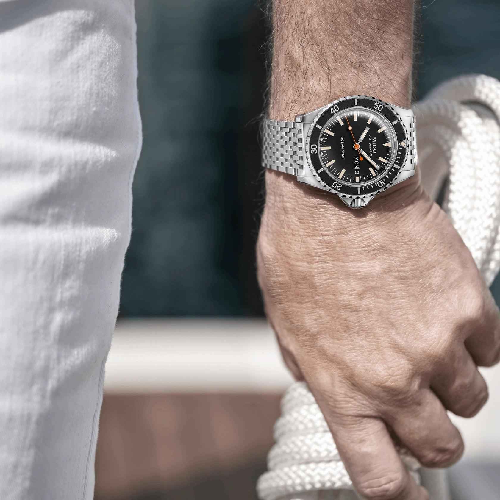 Orologio con quadrante nero e bracciale maglia d’acciaio al polso