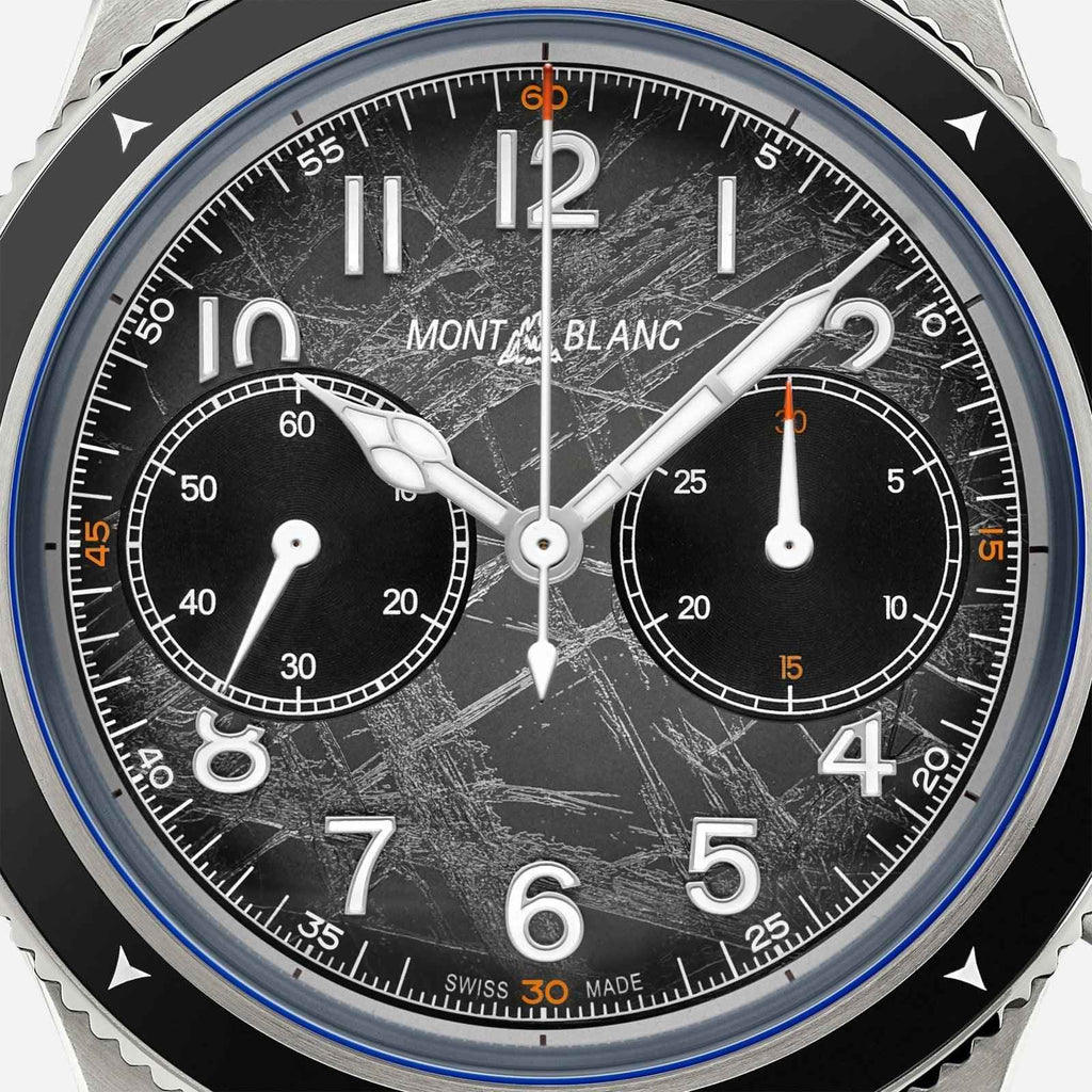 Quadrante cronografo nero con indici bianchi e lancette, dettagli blu sul bezel