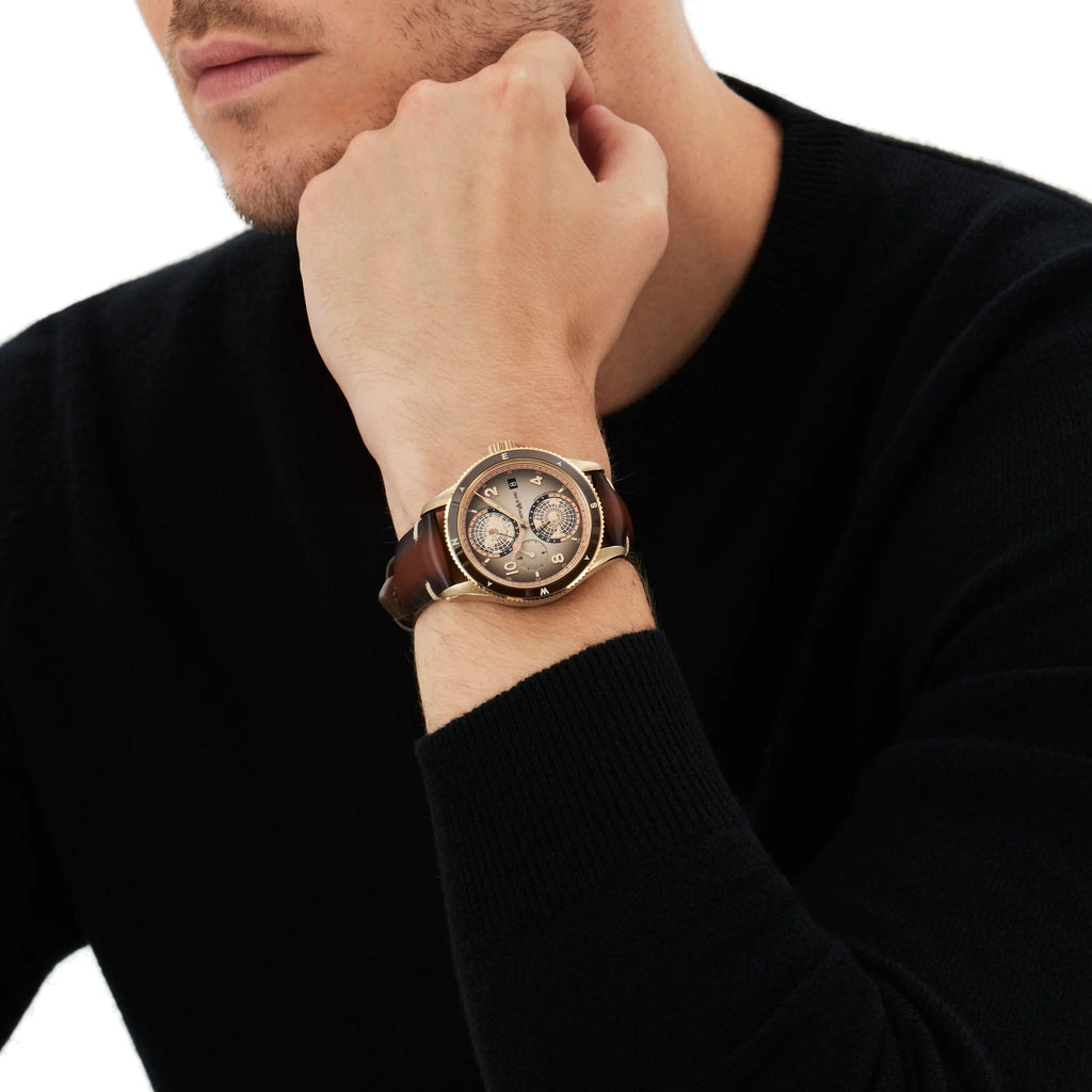 Orologio uomo al polso con cinturino marrone e cassa dorata, quadrante dettagliato