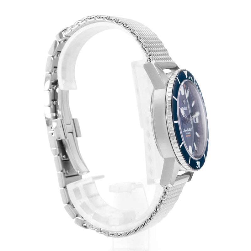 Orologio subacqueo con cassa d’acciaio e lunetta blu, bracciale in maglia, vista laterale.