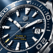Orologio TAG Heuer Aquaracer: quadrante blu a righe, lunetta girevole, datario.