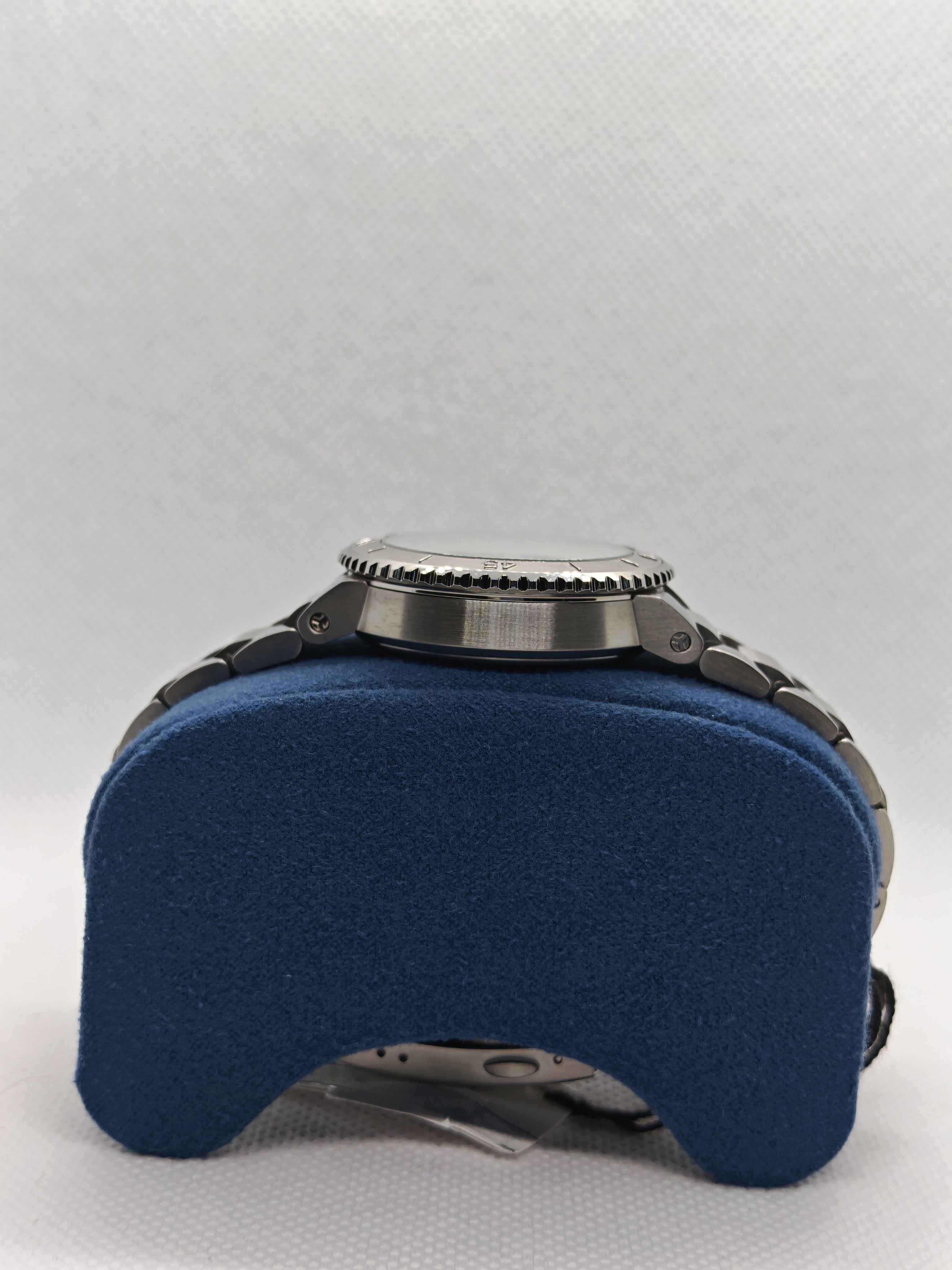 Cassa con corona dell’orologio e bracciale in acciaio su supporto blu