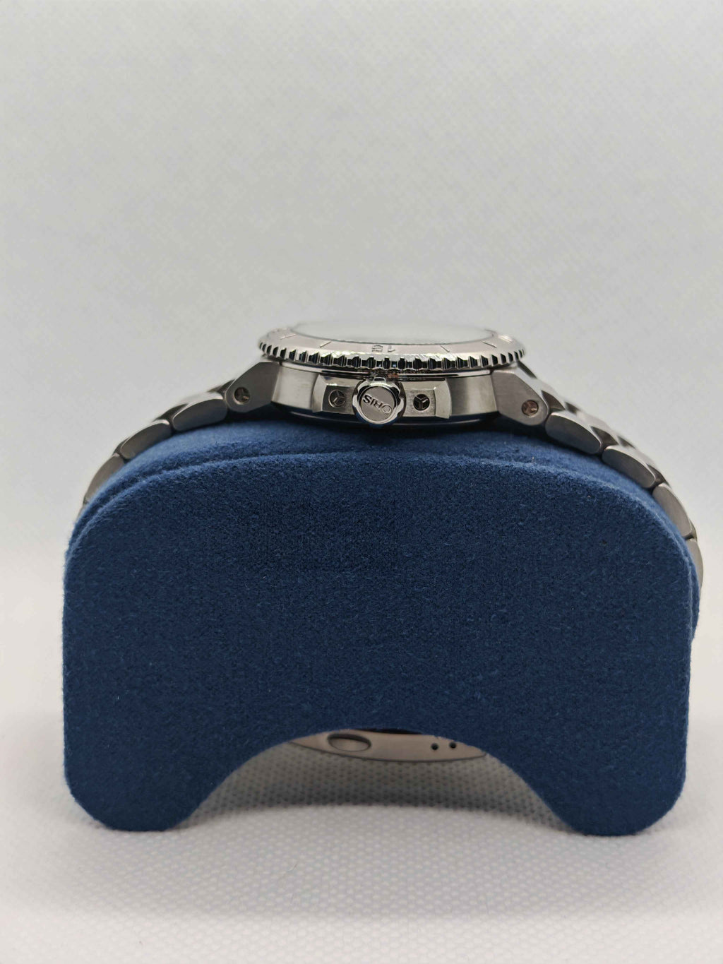 Cassa dell’orologio in acciaio con corona, su supporto blu