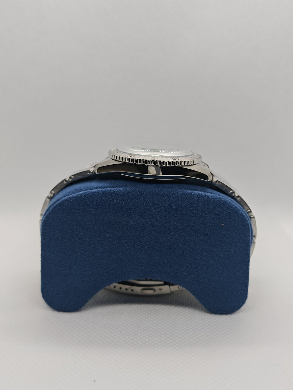 Orologio sub in acciaio con ghiera zigrinata, su supporto blu, quadrante non visibile