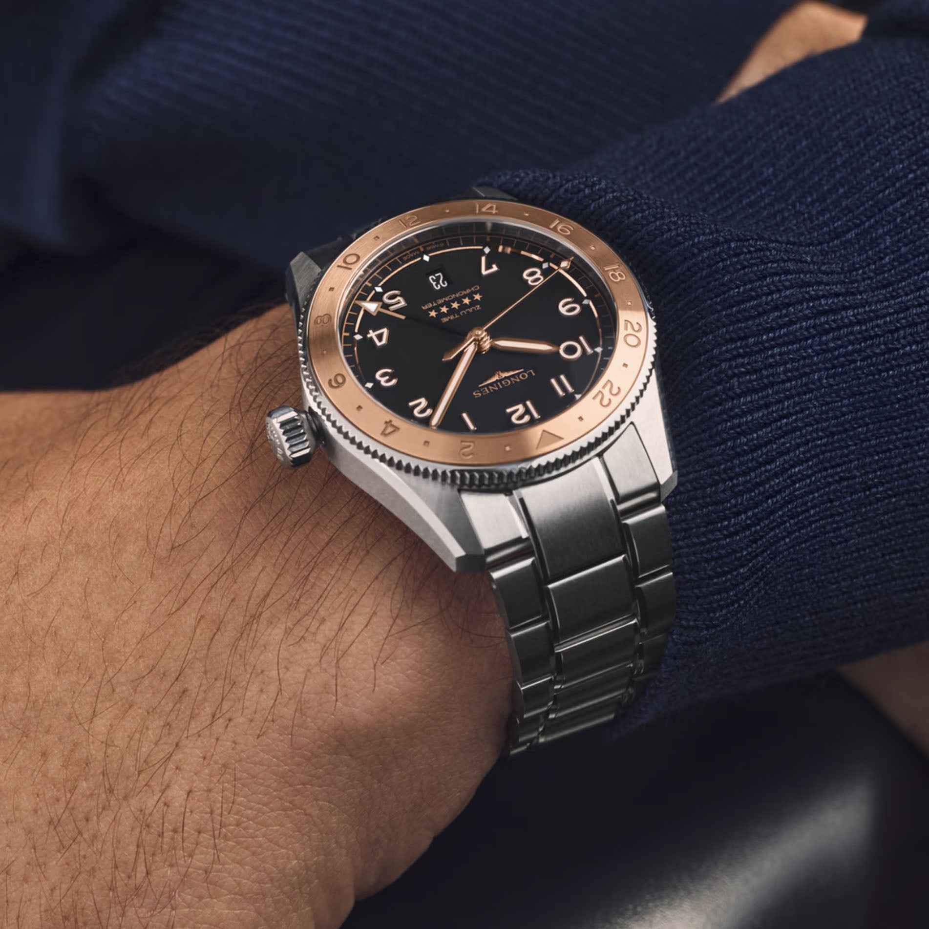 Orologio Longines al polso, quadrante nero con indici arancioni e cassa in acciaio