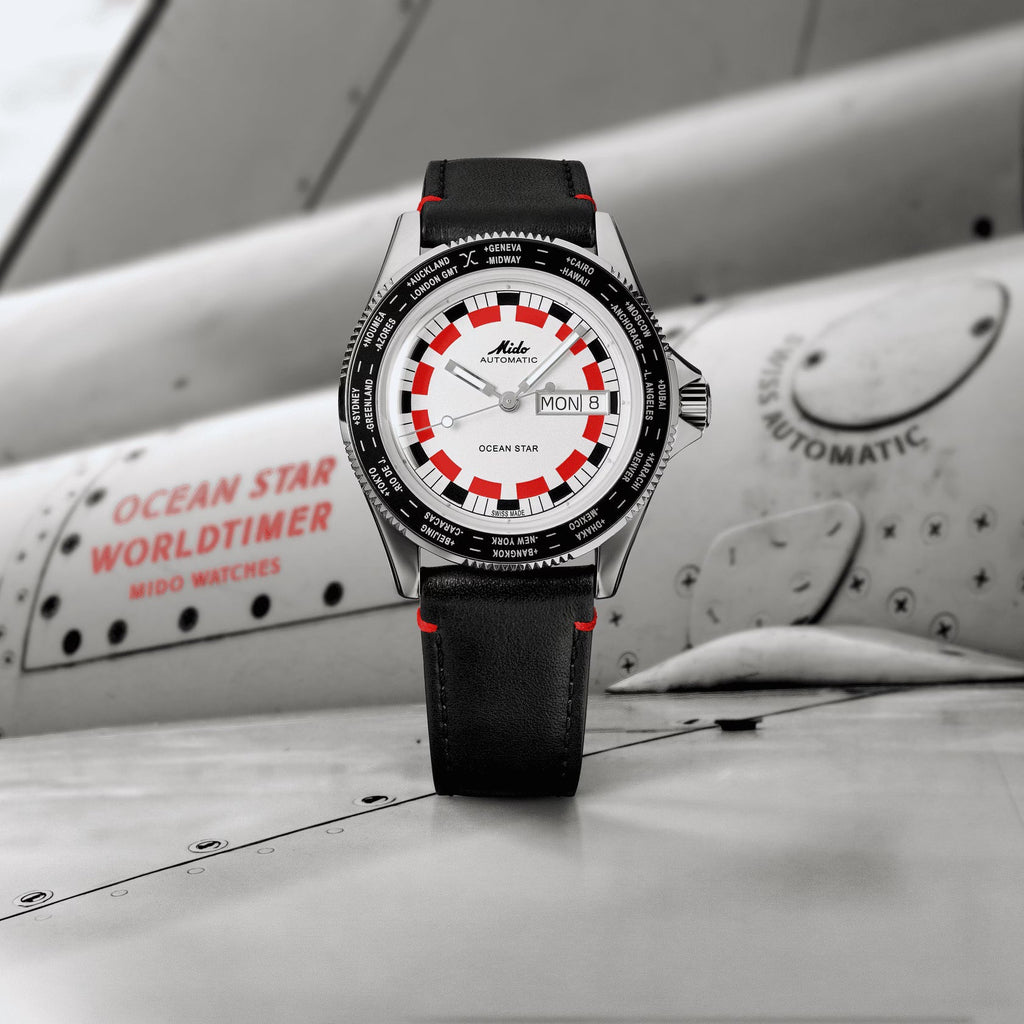 Orologio da polso in acciaio con quadrante bianco, indici rossi e cinturino nero.