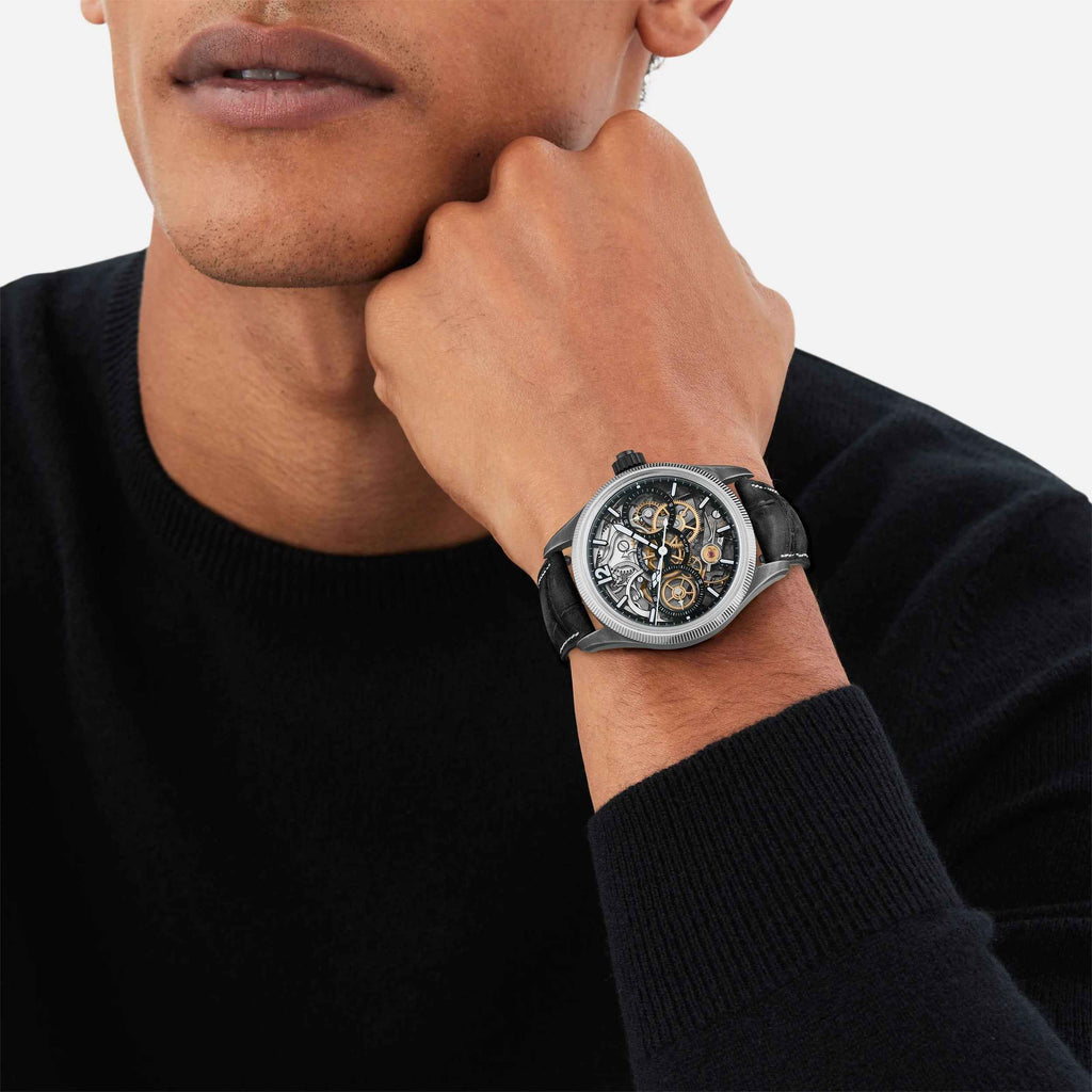 Orologio da polso sul polso: quadrante scheletrato e cinturino in pelle nera