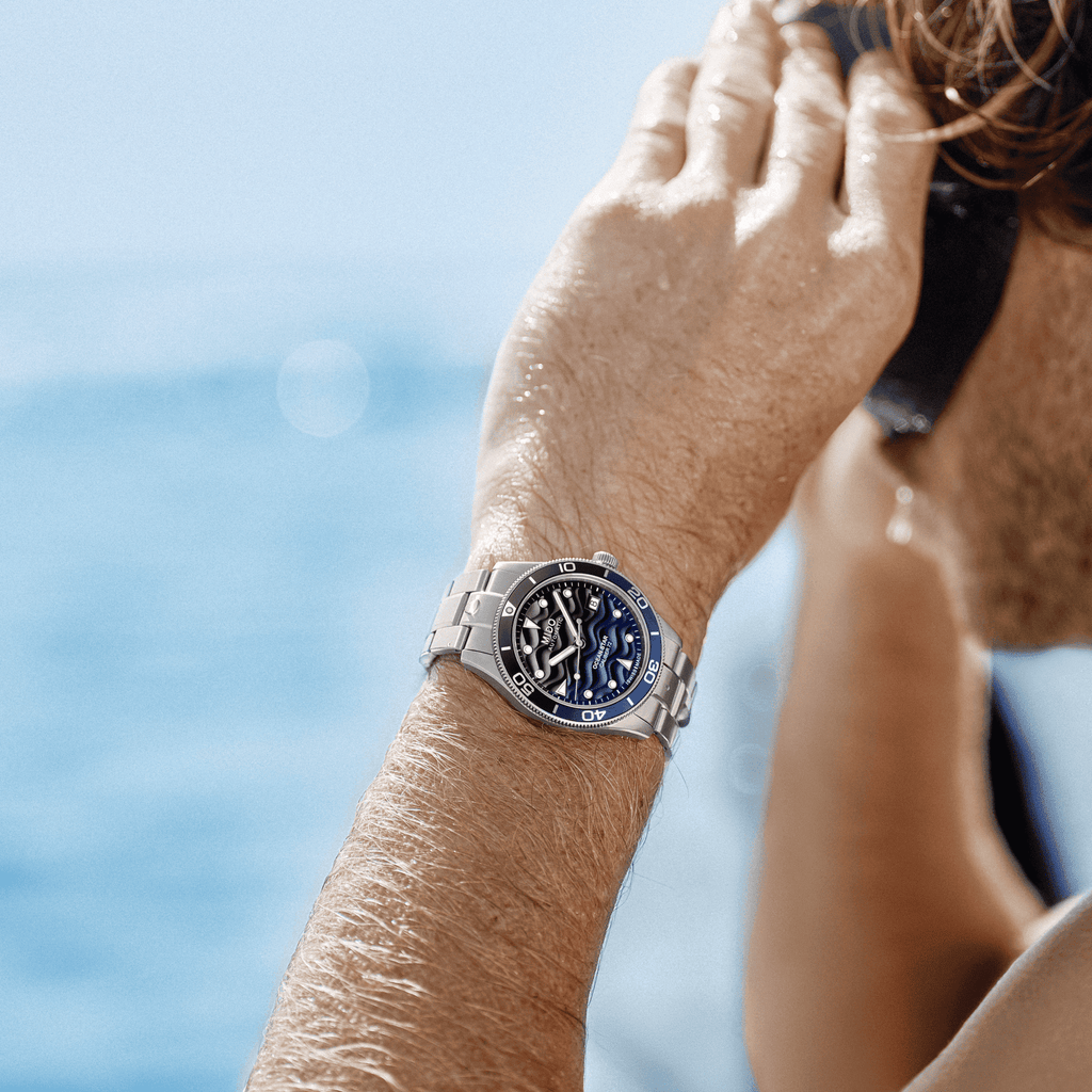 Orologio Mido con quadrante blu e bracciale in acciaio, al polso.